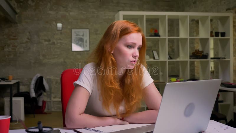 Le gingembre caucasien sûr femelle a le faire appel de vidéo à l'ordinateur portable et se reposer détendu sur le lieu de travail banque de vidéos