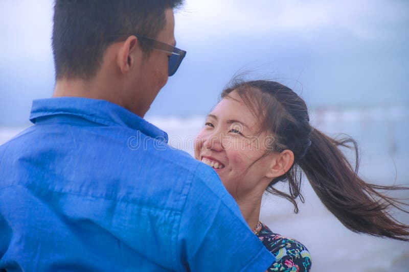 Le giovani coppie asiatiche cinesi felici e belle con la donna abbracciano il suo ragazzo romantico e stringono a sé sulla spiagg fotografia stock Le giovani coppie asiatiche cinesi felici e belle con la donna abbracciano il suo ragazzo romantico e stringono a sé sulla spiagg fotografia stock