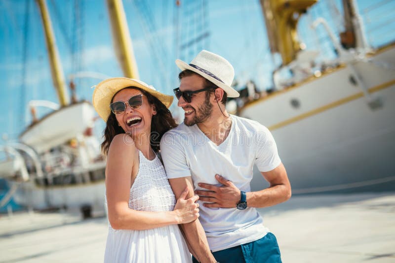Le giovani coppie felici che camminano dal porto di un mare turistico ricorrono fotografia stock libera da diritti Le giovani coppie felici che camminano dal porto di un mare turistico ricorrono fotografia stock libera da diritti