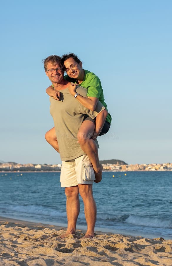 Le giovani coppie nel tramonto si accendono sulla spiaggia immagine stock Le giovani coppie nel tramonto si accendono sulla spiaggia immagine stock