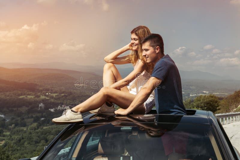 Le giovani coppie sul viaggio stradale viaggiano insieme in macchina e godono della vista della natura dalla cima
