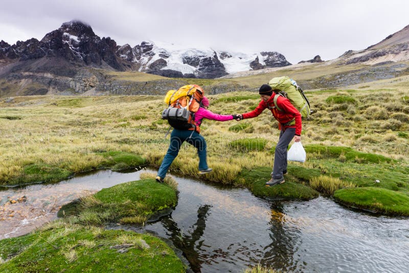 Le grimpeur de montagne masculin aide l'associé à traverser une rivière dans les Andes du Pérou image libre de droits Le grimpeur de montagne masculin aide l'associé à traverser une rivière dans les Andes du Pérou image libre de droits