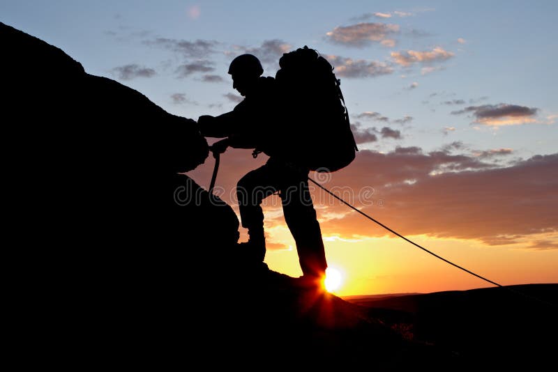 Le grimpeur va vers le haut sur le fond du coucher du soleil photo libre de droits Le grimpeur va vers le haut sur le fond du coucher du soleil photo libre de droits