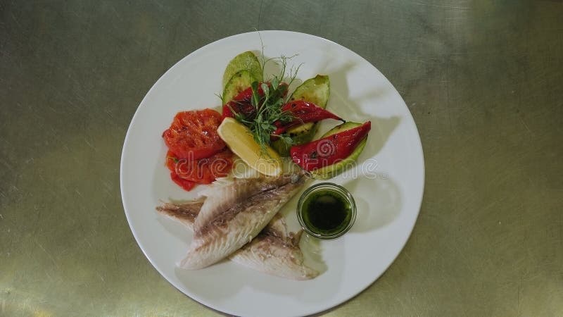 Le gros plan d'un délicieux plat avec des poissons a grillé les légumes et le citron d'une plaque.