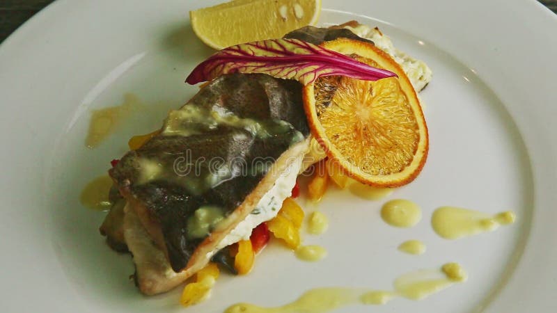 Le gros plan de vue de dessus a finement décorée du poisson de mer cuits au four sur les poivrons coupés en tranches tourne du pla banque de vidéos