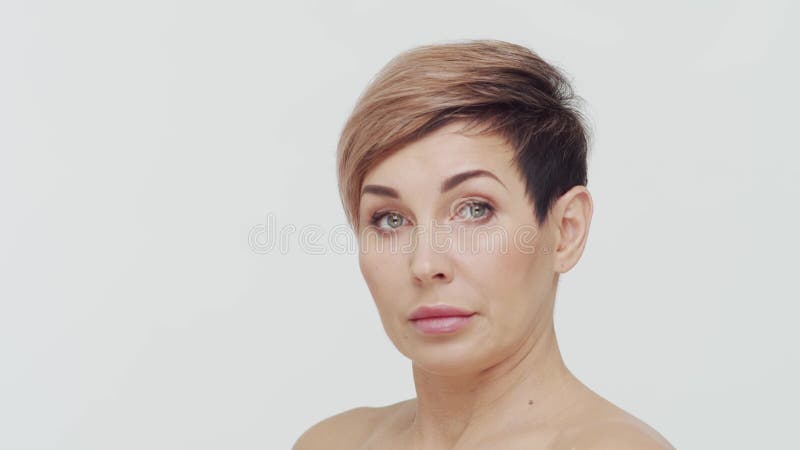 Le gros plan du milieu de la femme mûre au-dessus du bacjground blanc. Portrait de femme mûre. Les injections de beauté de chirurg banque de vidéos