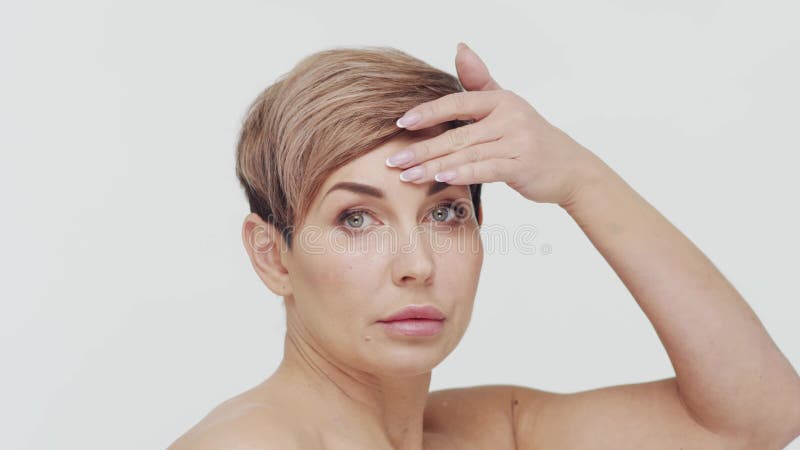 Le gros plan du milieu de la femme mûre au-dessus du bacjground blanc. Portrait de femme mûre. Les injections de beauté de chirurg banque de vidéos