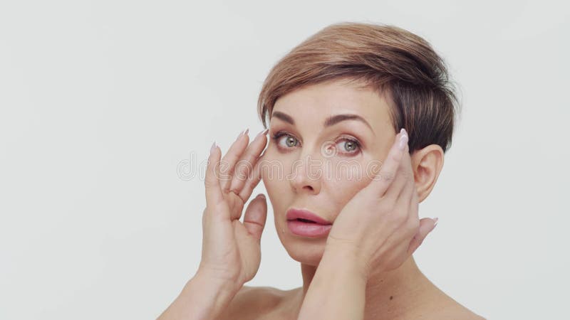 Le gros plan du milieu de la femme mûre au-dessus du bacjground blanc. Portrait de femme mûre. Les injections de beauté de chirurg banque de vidéos