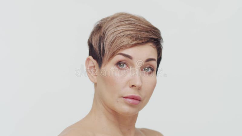 Le gros plan du milieu de la femme mûre au-dessus du bacjground blanc. Portrait de femme mûre. Les injections de beauté de chirurg banque de vidéos