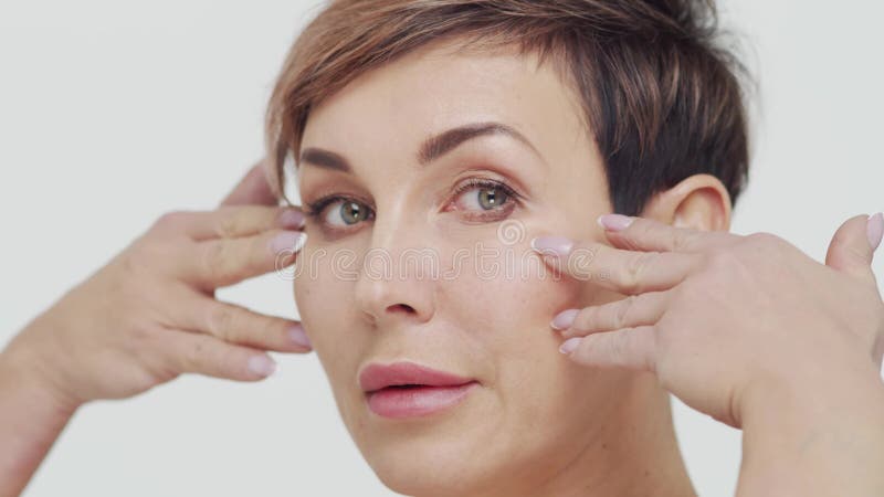 Le gros plan du milieu de la femme mûre au-dessus du bacjground blanc. Portrait de femme mûre. Les injections de beauté de chirurg clips vidéos