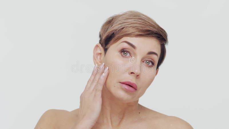 Le gros plan du milieu de la femme mûre au-dessus du bacjground blanc. Portrait de femme mûre. Les injections de beauté de chirurg banque de vidéos