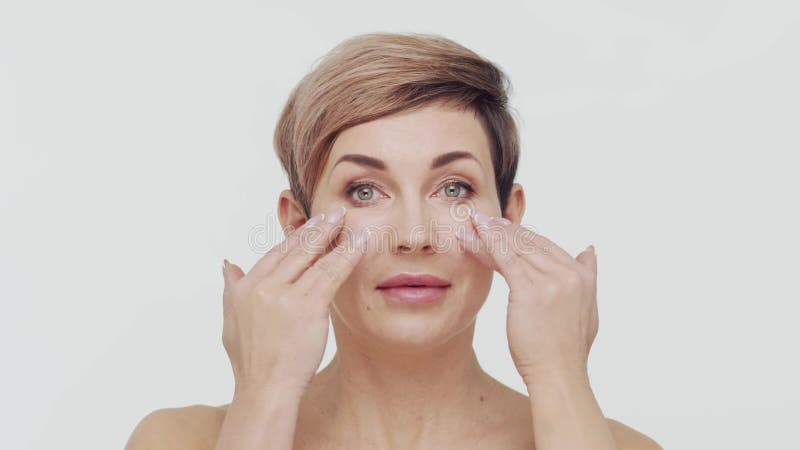 Le gros plan du milieu de la femme mûre au-dessus du bacjground blanc. Portrait de femme mûre. Les injections de beauté de chirurg banque de vidéos