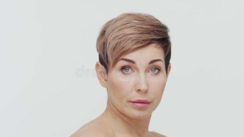 Le gros plan du milieu de la femme mûre au-dessus du bacjground blanc. Portrait de femme mûre. Les injections de beauté de chirurg banque de vidéos