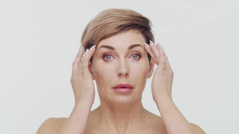 Le gros plan du milieu de la femme mûre au-dessus du bacjground blanc. Portrait de femme mûre. Les injections de beauté de chirurg clips vidéos