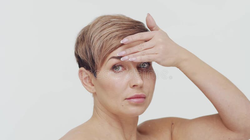 Le gros plan du milieu de la femme mûre au-dessus du bacjground blanc. Portrait de femme mûre. Les injections de beauté de chirurg banque de vidéos