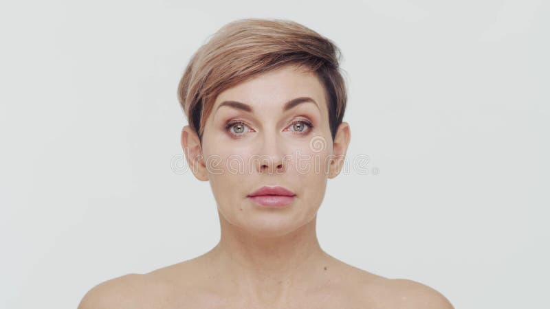 Le gros plan du milieu de la femme mûre au-dessus du bacjground blanc. Portrait de femme mûre. Les injections de beauté de chirurg banque de vidéos