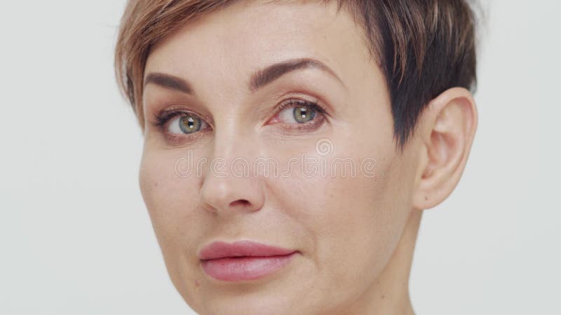 Le gros plan du milieu de la femme mûre au-dessus du fond blanc. Portrait de femme mûre. Les injections de beauté de chirurgie pla banque de vidéos