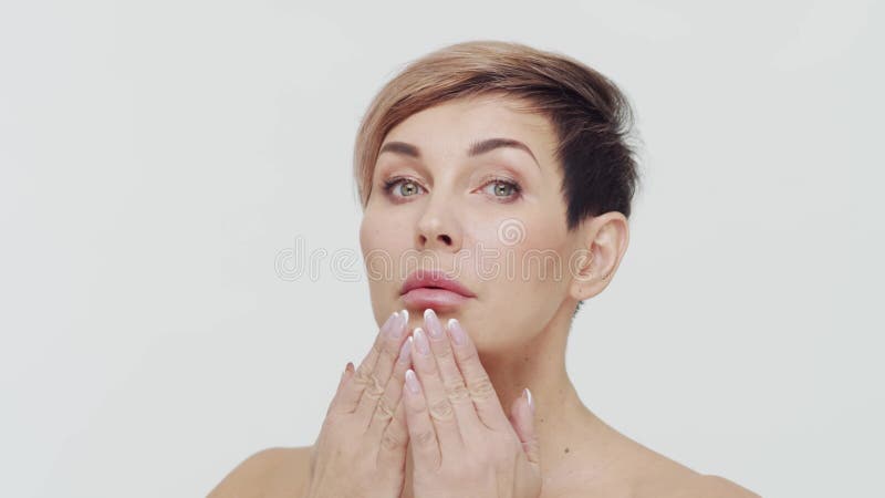 Le gros plan du milieu de la femme mûre au-dessus du fond blanc. Portrait de femme mûre. Les injections de beauté de chirurgie pla banque de vidéos