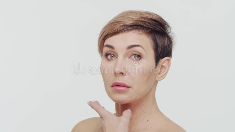 Le gros plan du milieu de la femme mûre au-dessus du fond blanc. Portrait de femme mûre. Les injections de beauté de chirurgie pla clips vidéos