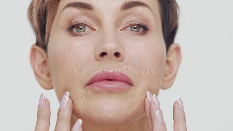 Le gros plan du milieu de la femme mûre au-dessus du fond blanc. Portrait de femme mûre. Les injections de beauté de chirurgie pla banque de vidéos