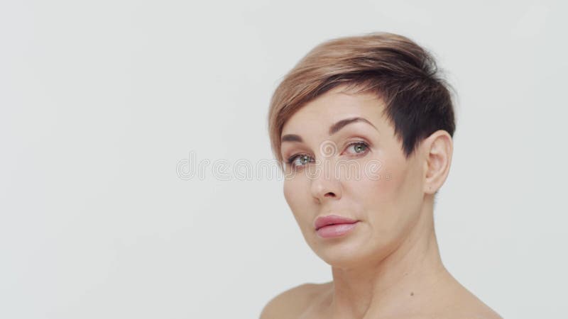 Le gros plan du milieu de la femme mûre au-dessus du fond blanc. Portrait de femme mûre. Les injections de beauté de chirurgie pla clips vidéos