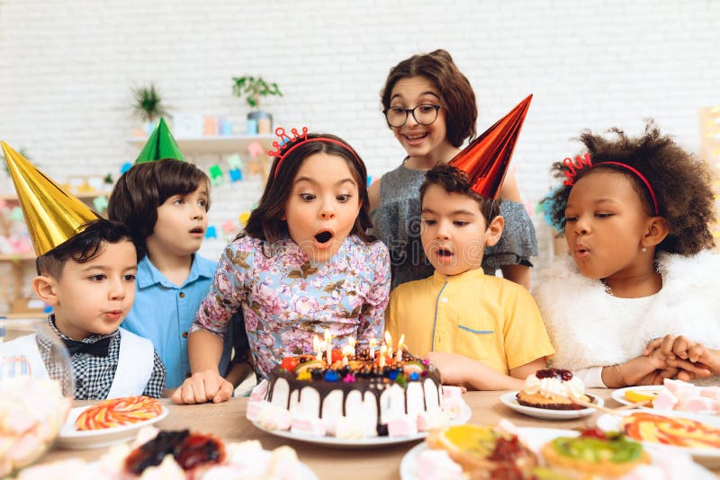 Le groupe d'enfants va souffler des bougies sur le gâteau Partie de joyeux anniversaire photographie stock Le groupe d'enfants va souffler des bougies sur le gâteau Partie de joyeux anniversaire photographie stock