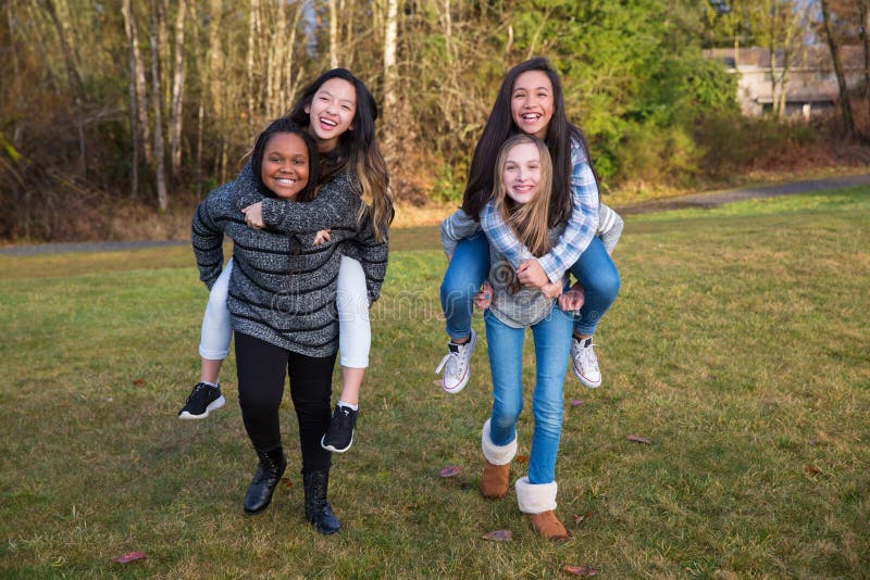 Le groupe de quatre enfants jouant et donnant sur le dos monte image libre de droits Le groupe de quatre enfants jouant et donnant sur le dos monte image libre de droits