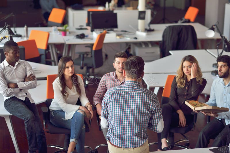 Le groupe des jeunes dans le bureau moderne ont la réunion et la séance de réflexion d'équipe tout en travaillant à l'ordinateur images stock