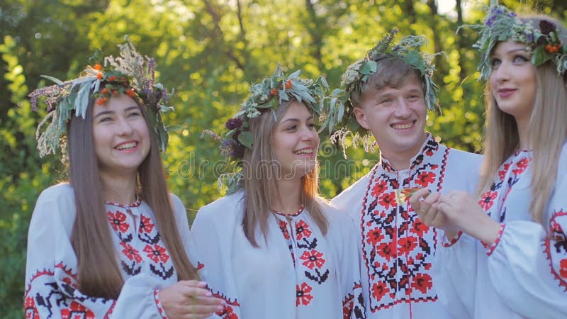 Le groupe des jeunes dans des costumes nationaux slaves célèbrent le solstice d'été Un groupe de filles et de garçons parlant et banque de vidéos