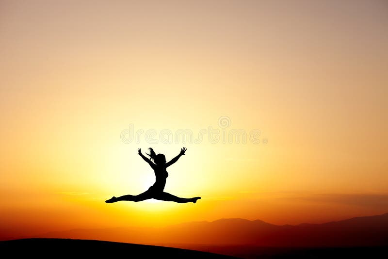 Le gymnaste sautant dans le coucher du soleil