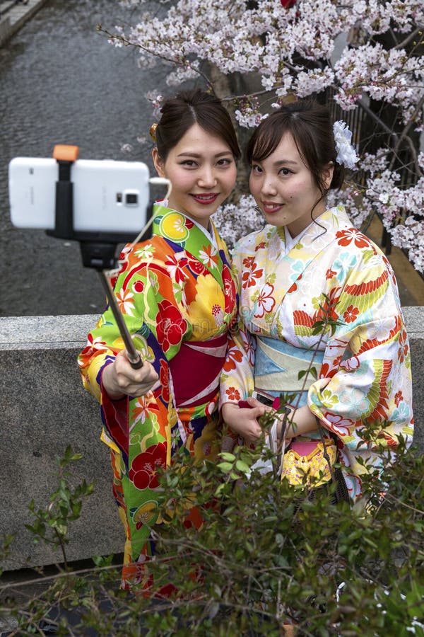 Le Japon, Kyoto, 04/05/2017 Les jeunes filles japonaises dans le kimono prennent un selfie sur le fond de Sakura photo stock Le Japon, Kyoto, 04/05/2017 Les jeunes filles japonaises dans le kimono prennent un selfie sur le fond de Sakura photo stock