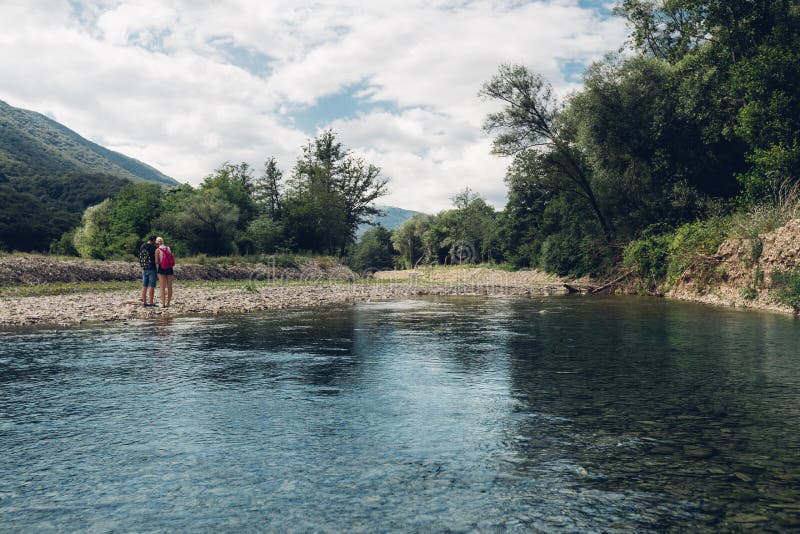 Le jeune couple marche le long de l'été de rivière, ensemble vue arrière de concept photographie stock Le jeune couple marche le long de l'été de rivière, ensemble vue arrière de concept photographie stock
