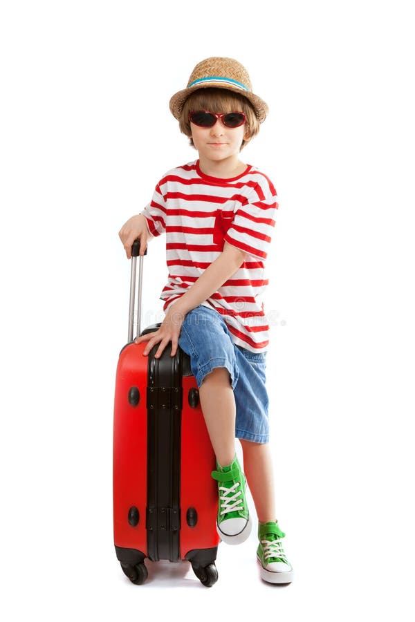 Le jeune garçon s'assied sur la valise rouge photo stock Le jeune garçon s'assied sur la valise rouge photo stock