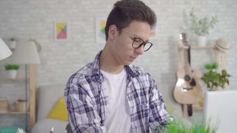 Le jeune homme asiatique de portrait s'asseyant à l'ordinateur portable a trouvé une solution pour le succès au travail ou à l'éc clips vidéos