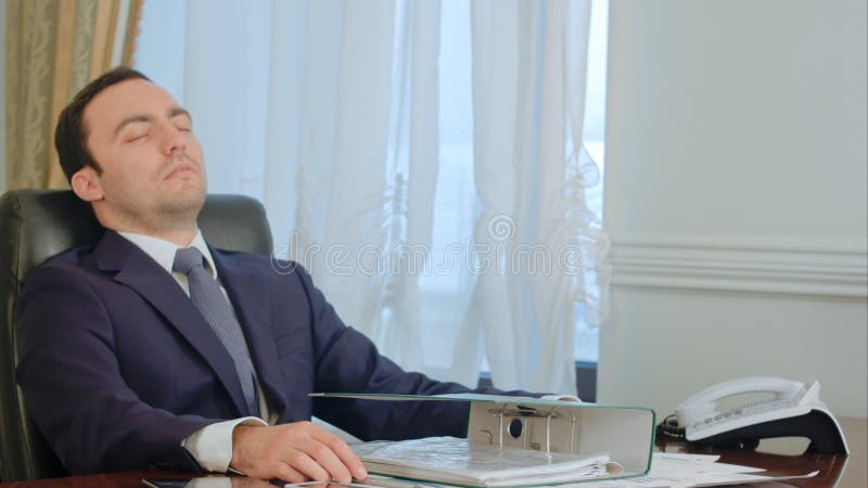 Le jeune homme d'affaires de sommeil s'est réveillé par l'appel téléphonique dans le bureau photos stock Le jeune homme d'affaires de sommeil s'est réveillé par l'appel téléphonique dans le bureau photos stock
