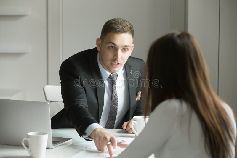 Le jeune homme d'affaires indique une erreur dans un papier photo stock Le jeune homme d'affaires indique une erreur dans un papier photo stock
