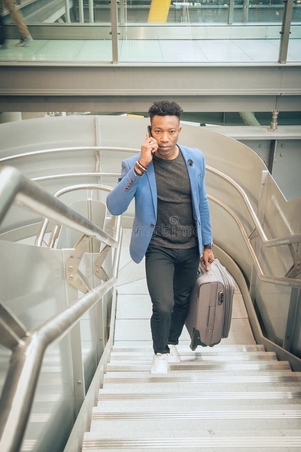 Le jeune homme d'affaires monte des escaliers dans l'aéroport parlant par t images stock Le jeune homme d'affaires monte des escaliers dans l'aéroport parlant par t images stock