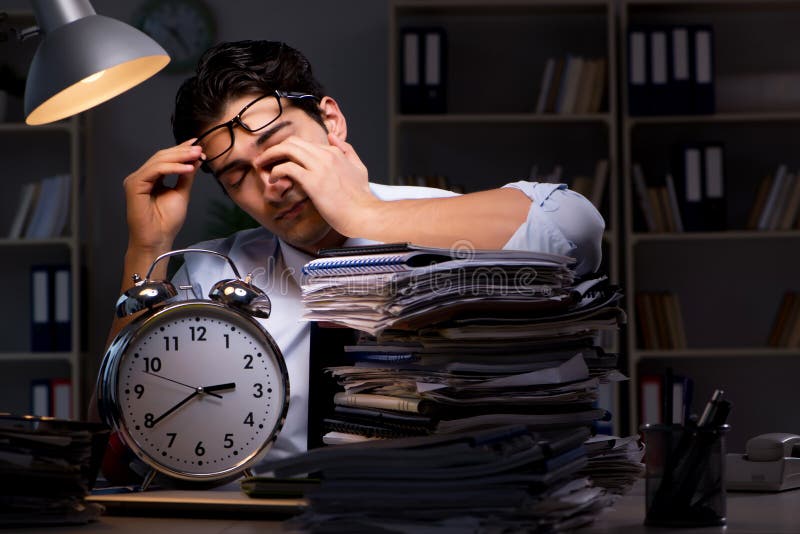 Le jeune homme d'affaires travaillant des heures supplémentaires tard dans le bureau photos stock Le jeune homme d'affaires travaillant des heures supplémentaires tard dans le bureau photos stock