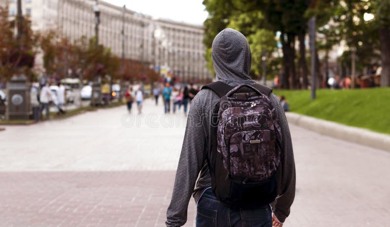 Le jeune homme descend la rue d'une grande ville photo stock Le jeune homme descend la rue d'une grande ville photo stock