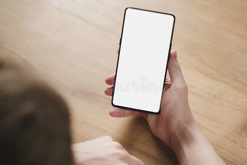 Le jeune homme remet tenir le smartphone avec l'écran blanc vide images libres de droits Le jeune homme remet tenir le smartphone avec l'écran blanc vide images libres de droits