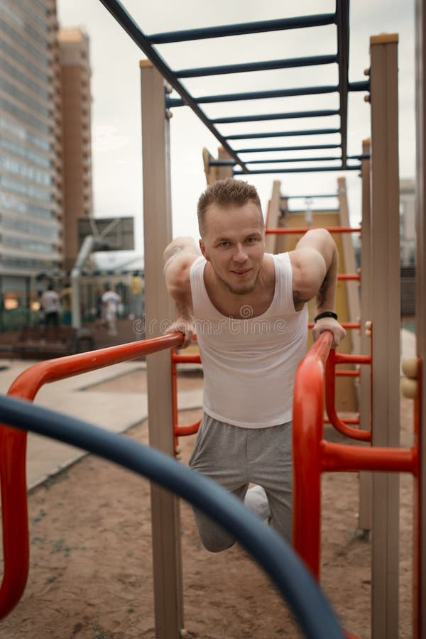 Le jeune homme énergique font des exercices dehors dans la place de sport au kee photographie stock libre de droits Le jeune homme énergique font des exercices dehors dans la place de sport au kee photographie stock libre de droits