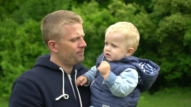 Le jeune père heureux tient le petit fils sur des mains et joue en parc