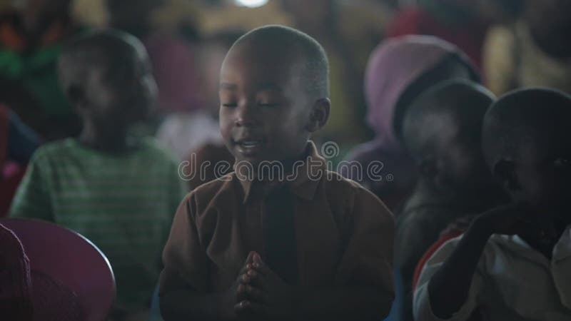 LE KENYA, KISUMU - 20 MAI 2017 : Portrait du garçon africain heureux s'asseyant à l'intérieur avec le groupe d'enfants et de dans clips vidéos
