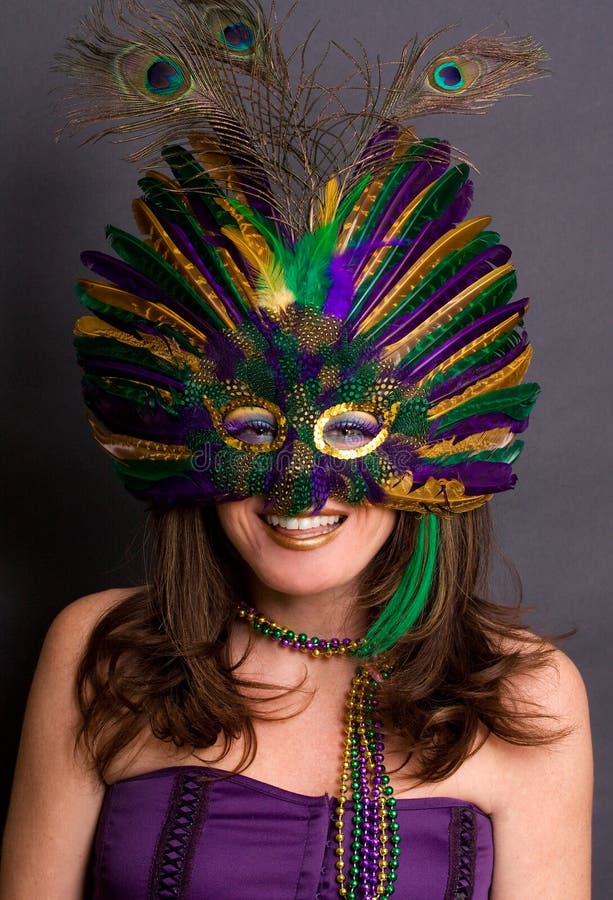 A portrait of a happy young woman wearing a Mardi Gras mask, beads, and makeup. A portrait of a happy young woman wearing a Mardi Gras mask, beads, and makeup