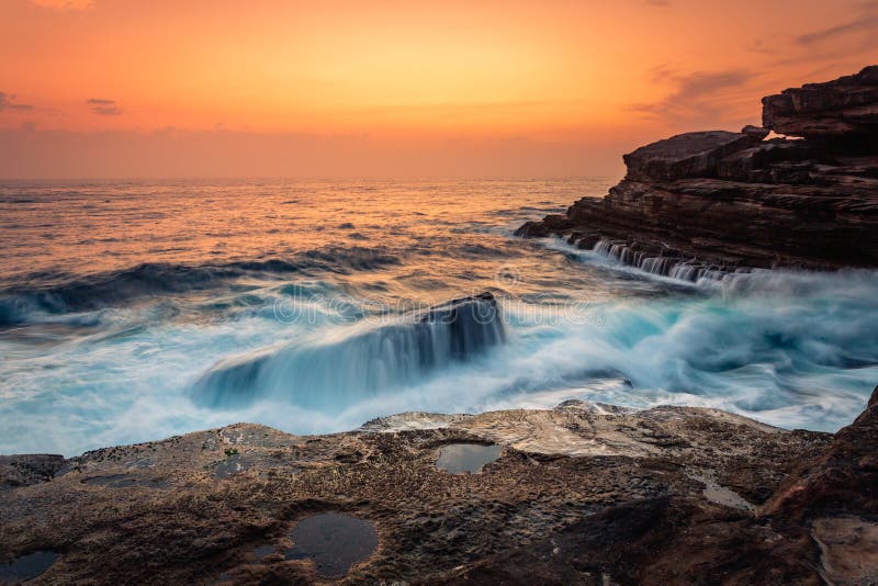 Le lever de soleil et les vagues de stupéfaction se brisent au-dessus des roches sur la côte de Sydney image stock Le lever de soleil et les vagues de stupéfaction se brisent au-dessus des roches sur la côte de Sydney image stock