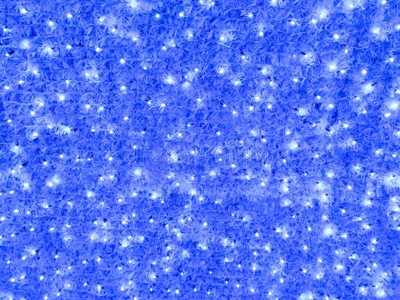 Le luci della stagione natalizia blu in inverno coperte di neve per uno sfondo confortevole o una trama all'esterno della città immagini stock Le luci della stagione natalizia blu in inverno coperte di neve per uno sfondo confortevole o una trama all'esterno della città immagini stock