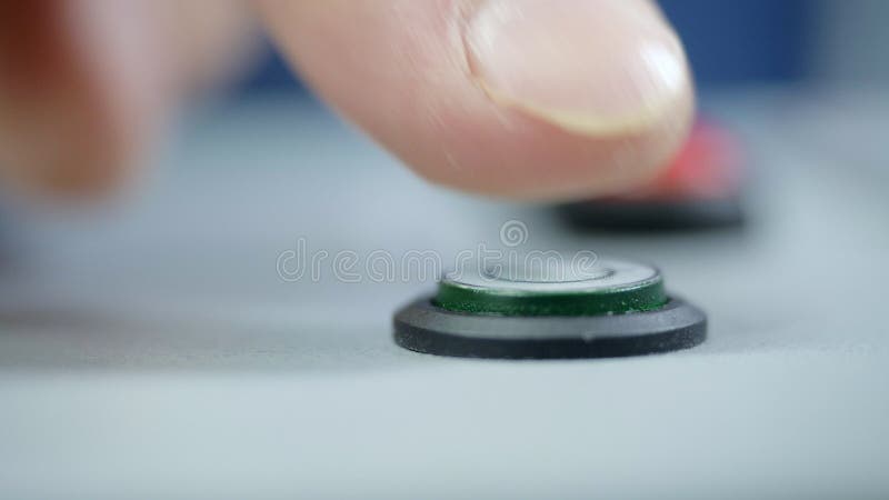 Le macro doigt appuie sur doucement le bouton de vert pour mettre en marche la machine banque de vidéos