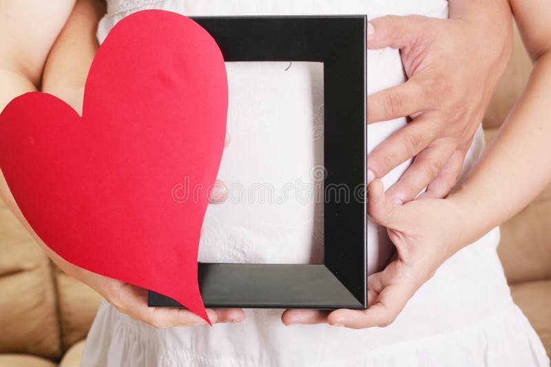 Le mani che abbracciano una donna incinta si gonfiano con le sue mani che tengono la a fotografia stock libera da diritti Le mani che abbracciano una donna incinta si gonfiano con le sue mani che tengono la a fotografia stock libera da diritti