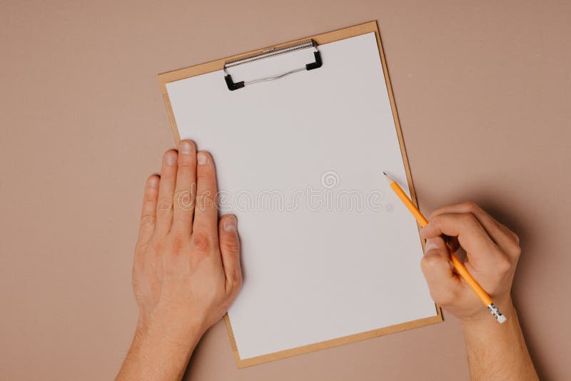 Le mani dell'uomo che scrivono su un bordo di clip su un fondo grigio fotografie stock libere da diritti Le mani dell'uomo che scrivono su un bordo di clip su un fondo grigio fotografie stock libere da diritti
