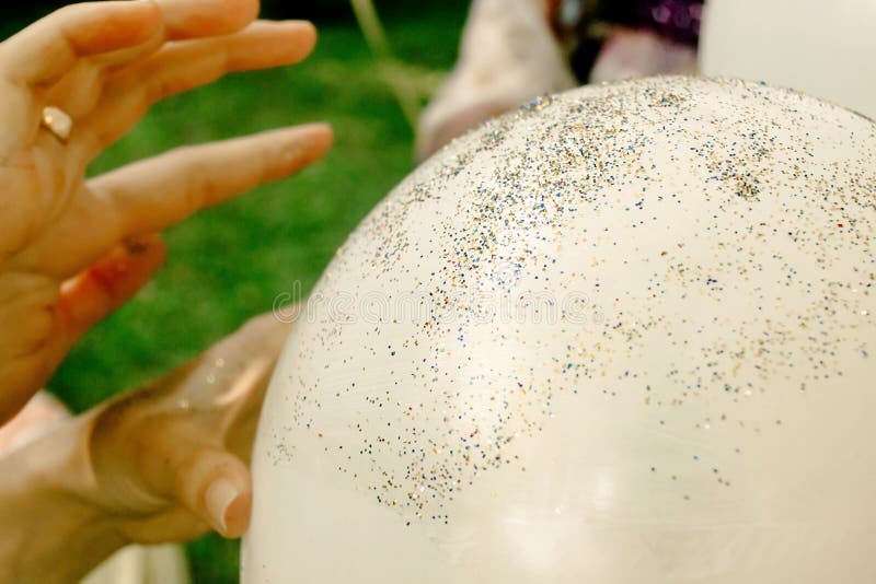 Le mani della donna che decorano i grandi palloni bianchi con le scintille brillano immagine stock libera da diritti Le mani della donna che decorano i grandi palloni bianchi con le scintille brillano immagine stock libera da diritti